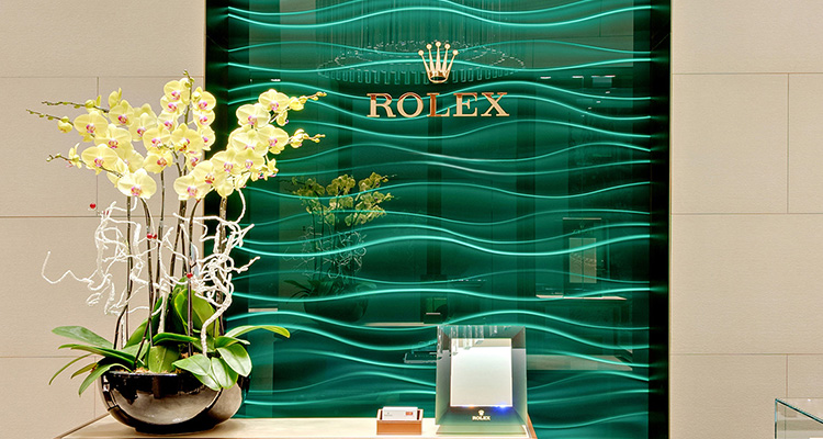 Im Rolex Showroom von Juwelier Freisfeld gibt es eine grüne Glasvertäfelung mit einem großen goldenen Rolex Logo 