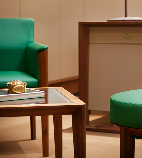 Ein grüner Sessel in einem Rolex Showroom mit elegantem Beistelltisch für die Präsentation von Uhren