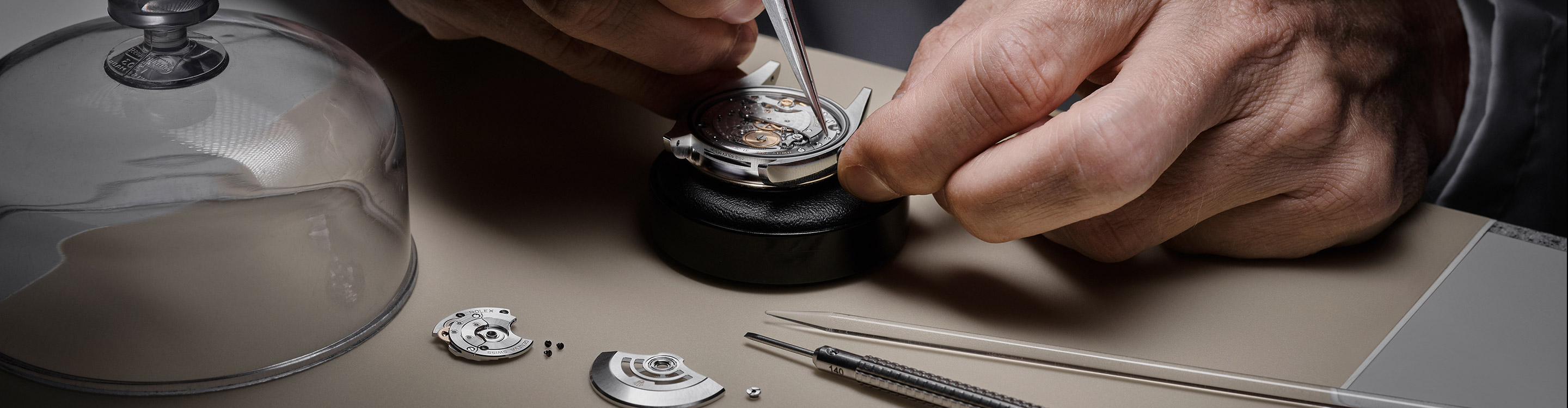 Ein Uhrmacher zerlegt das Werk einer Rolex Uhr in seine Kleinteile