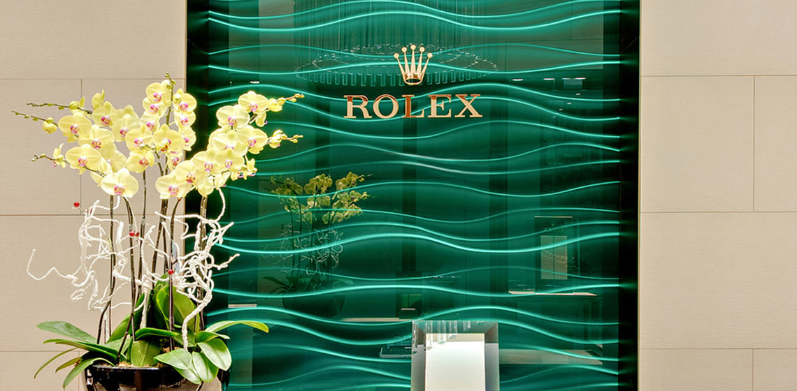 Im Rolex Showroom von Juwelier Freisfeld gibt es eine grüne Glasvertäfelung mit einem großen goldenen Rolex Logo