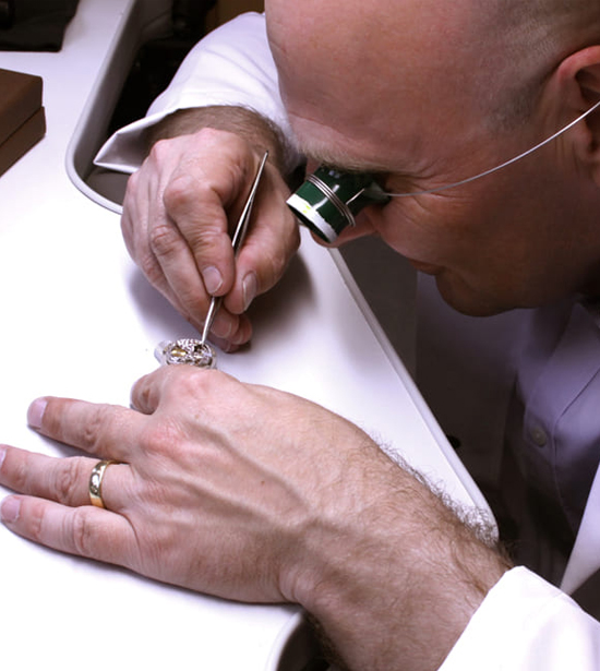 Uhrmacher mit Augenlupe arbeitet am offenen Werk einer Uhr von Rolex