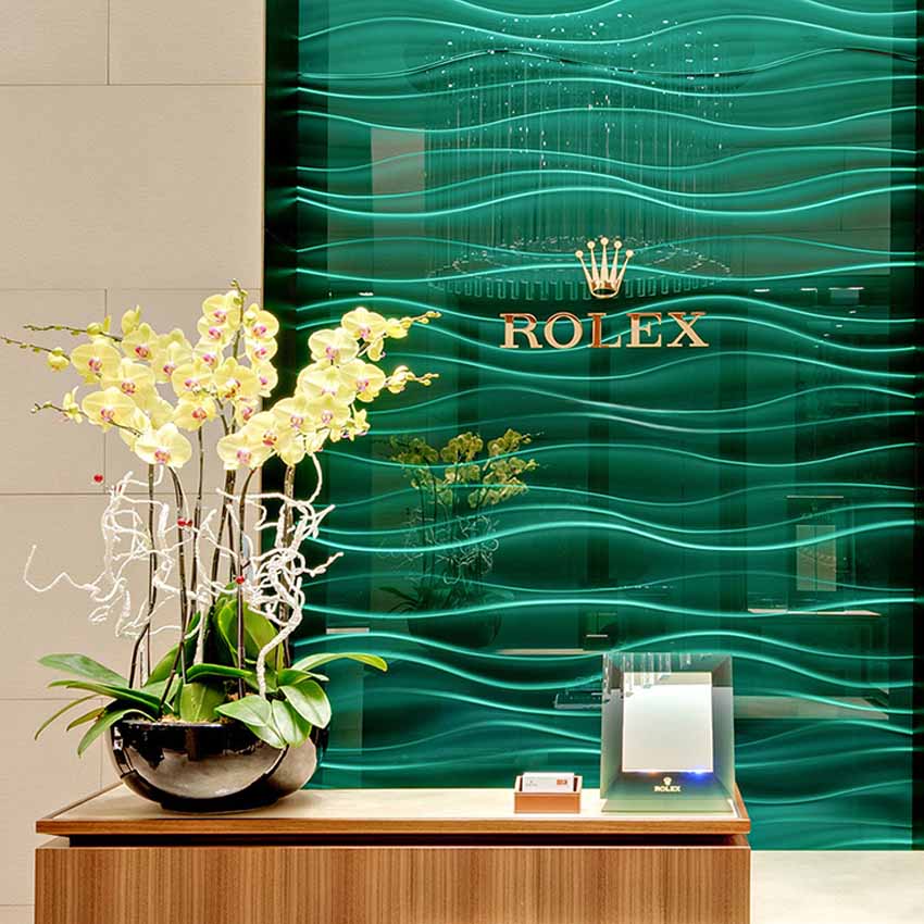 Im Rolex Showroom von Juwelier Freisfeld gibt es eine grüne Glasvertäfelung mit einem großen goldenen Rolex Logo